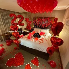 Another angle of our romantic room decoration service, showing the full scope of the transformation. We cover the ceiling with helium balloons and create intricate heart patterns on the floor with rose petals and LED candles.