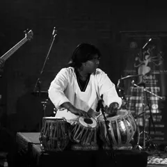 A black and white shot of me performing on stage with my fusion band. You can see the neck of a bass guitar in the background, indicating a modern band setup with drums and other instruments.