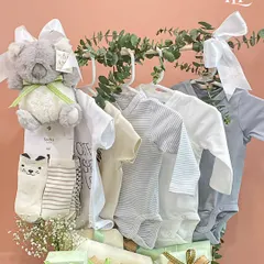 Another angle of the neutral-toned baby clothing hamper, highlighting the soft fabrics and the elegant arrangement with eucalyptus leaves.