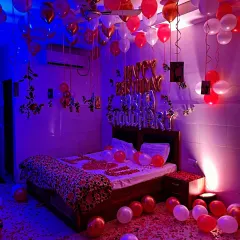 A personalized romantic room setup with the name spelled out in foil balloons above the bed.