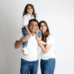 Capturing the pure joy of family life. This classic family portrait with the child on dad's shoulders is full of laughter and connection, shot against a clean white background to keep the focus entirely on their happy expressions.