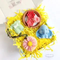A curated gift box for a baby shower, featuring a clay pot candle, baby elephant candle, onesie sachet, and daisy sachet.