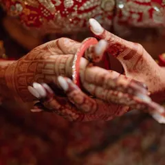 A close-up of the intricate details for Nikita's wedding day. The traditional red bangles, or 'chooda', paired with her mehndi, are essential elements of the classic Indian bridal look.