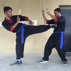 Two students practice a kicking and blocking sequence. This drill develops balance, coordination, and the ability to defend against lower-body attacks in a close-quarters fight.