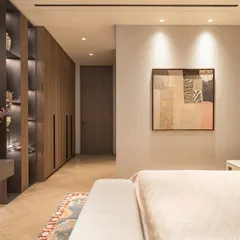 A wider view of the guest bedroom, showing the seamless integration of the wardrobe and TV unit. The design prioritizes a clutter-free environment, ensuring a sense of calm and order.