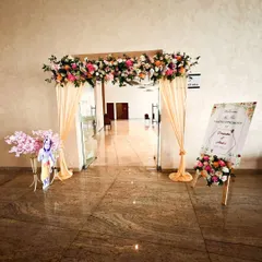 A welcoming entrance for a naming ceremony, featuring a floral arch over the doorway, peach drapes, and a custom welcome sign.