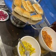 All the essential accompaniments for Pav Bhaji: soft buttered pav, chopped onions, a sprinkle of spicy garlic chutney, and a wedge of lemon.
