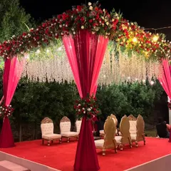 I design stunning wedding mandaps that become the heart of your ceremony. This outdoor mandap setup combines rich red and white florals with elegant draping and hanging floral strings for a truly grand and traditional feel.