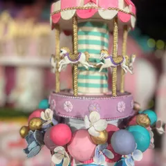 The carousel topper on this carnival cake is a masterpiece in itself, with tiny horses and intricate gold detailing.