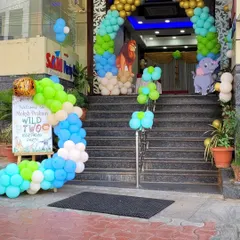 The grand entrance to a jungle-themed birthday party. A colorful balloon arch with lion and elephant cutouts welcomes guests up the stairs to the celebration.