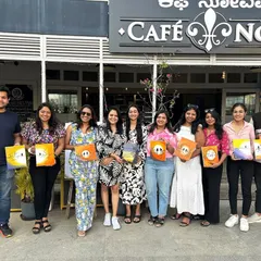 A fantastic corporate team outing, with the group posing with their finished paintings outside Cafe Noir.