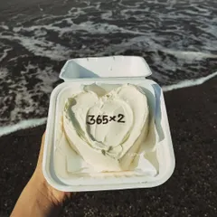A heart-shaped bento cake with "365x2" for a second anniversary, pictured beautifully against a beach backdrop.
