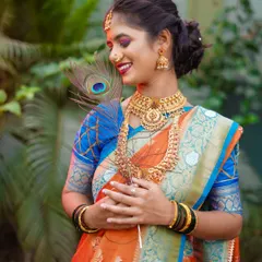 Incorporating simple props like this peacock feather can add a layer of symbolism and elegance to a bridal portrait. It complements the rich colors of her saree and her graceful posture, creating a classic and beautiful image.