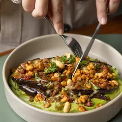 Here, aubergine is grilled until it's like velvet. Our Miso Grilled Aubergine is served on a bed of cashew tahini and green goddess sauce, then topped with a savory granola for a delightful crunch.