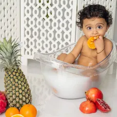 A healthy snack and a warm bath all in one. This little one is enjoying our fruit splash session, a fun and unique way to capture playful toddler moments.
