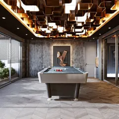 Another view of our sophisticated game room. This angle highlights the concrete-finish accent wall and the ample natural light from the large glass windows, creating a perfect balance of edgy and inviting.