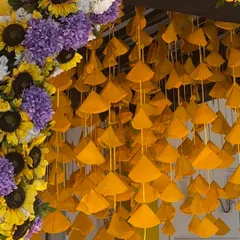 A unique and vibrant detail for a Haldi entrance. This close up shows the hanging yellow fabric cones and the lush arch of sunflowers and purple flowers that created a memorable entryway.
