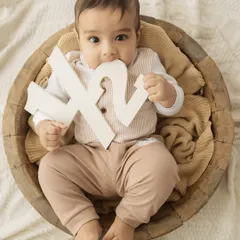 A cheeky little taste. This six-month-old is exploring his half-birthday sign, a fun and authentic moment from his milestone session.