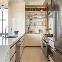 This open-shelf kitchen is a perfect example of functional style. The white marble backsplash and countertop extend up the wall, creating a seamless and luxurious look, while open shelves keep everyday items accessible and on display.
