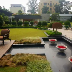 Another perspective of the same garden, showing the harmonious relationship between the dark, reflective water surface, the warm wood of the deck, and the vibrant green lawn. Every element is placed to create a cohesive and balanced composition.