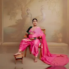 Seated on a traditional wooden chair with a painted peacock backdrop, this portrait is a celebration of Indian artistry and the grace of motherhood. The flowing saree adds a touch of royalty.