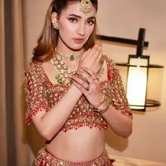 A close-up of a modern red lehenga look, focusing on the intricate blouse embroidery and the perfectly paired minimal jewelry. Comfort and beauty, hand in hand.