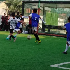 A young player skillfully dribbling past defenders, showcasing the technical ability we instill in our trainees.