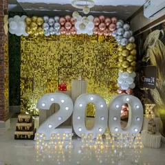 A grand 200k subscriber celebration with a gold shimmer wall. The decor features large marquee numbers, a metallic balloon arch, and decorative props.