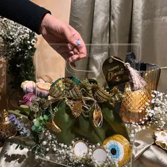 This elegant Diwali hamper features a beautiful potli filled with goodies, presented in a clear acrylic bag. The evil eye charm adds a modern, protective touch to this festive gift.