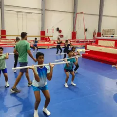 Catch 'em young, teach 'em young. Guiding a group of young gymnasts through a squatting technique session using PVC pipes to ensure proper form and movement patterns.