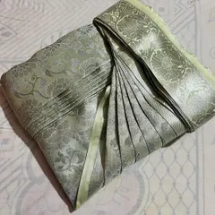 A light green Banarasi silk saree with intricate silver work, folded to showcase its beauty while keeping it safe.