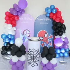 A joint Spider-Man themed birthday for twins. The setup features two separate arched backdrops for each child, with colorful balloon arrangements and a spider-web-themed plinth in the center.