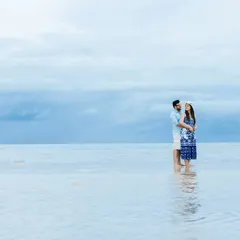 A romantic embrace in the tranquil sea during a beach pre-wedding session. The soft blue and grey tones of the water and sky give this photo a dreamy quality.