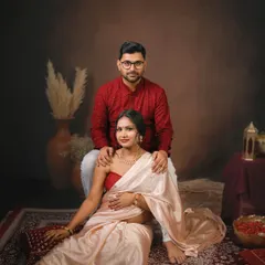 An elegant portrait of an expecting couple in a beautifully styled traditional setting. The earthy tones and classic attire create a timeless and regal feel.