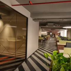 The bold black-and-white striped flooring at the Lohia Designco office creates a strong visual pathway through the workspace. This general contracting project included integrating biophilic elements like planters to soften the modern design.