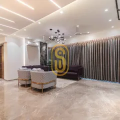 A wide-angle view of the living room, emphasizing the expansive marble flooring and the sophisticated lighting design. The combination of a central chandelier and linear ceiling lights provides layered illumination.