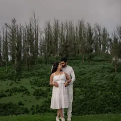 A wide, cinematic shot of the couple against the backdrop of Ooty's rolling green hills and tall trees. This photo captures the scale and beauty of the landscape, making their embrace feel even more special.