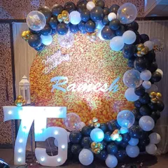 For this 75th birthday, we used a textured gold backdrop with a circular balloon arch in black, white, and gold. The large marquee numbers and confetti balloons add a touch of modern celebration to the classic color scheme.