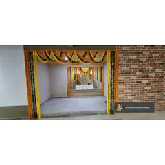 A simple and traditional mandir setup inside a corporate office for Diwali pooja. The entrance to the pooja room is framed with classic yellow and orange marigold garlands.