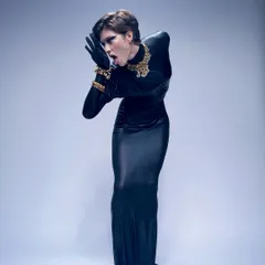 A dramatic, full-body pose for a high-fashion shoot. The look features a bold, graphic black eyeliner and a sculpted pixie haircut, creating a powerful and androgynous silhouette.