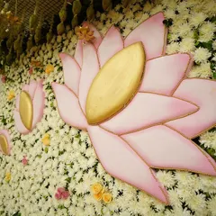 A close-up of the custom lotus cutouts against a dense wall of white flowers. These small, thoughtful details are central to our design philosophy, adding depth and personality to the event decor.