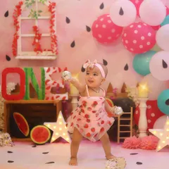 Dancing with joy! This little one is having the best time at her watermelon-themed party, surrounded by pink and green balloons and adorable props.