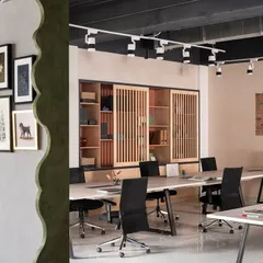 This partition wall serves a dual purpose. Aesthetically, its lime wash texture and scalloped edge provide a canvas for an evolving art gallery. Functionally, it holds large dashboards for my team to track project progress.