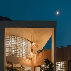 At night, the balcony garden becomes a glowing feature. The warm interior light illuminates the plants and the curved glass block wall, creating a magical aura from the outside.