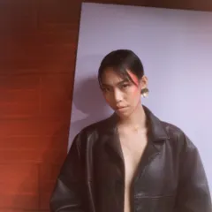 A modern editorial look featuring a bold sweep of red blush draped from the temple to the cheek, creating a strong, graphic shape.