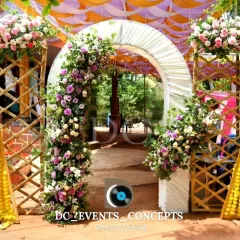 A beautiful outdoor entrance combining a rustic bamboo structure with a classic floral arch. The mix of textures and vibrant flowers creates a unique and welcoming pathway.