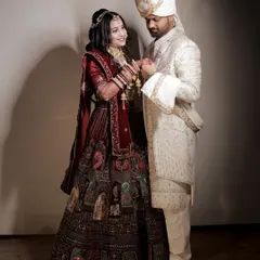 A classic, full-length portrait of the couple holding hands and sharing a gentle look. The bride's magnificent lehenga and the groom's elegant sherwani are beautifully displayed.