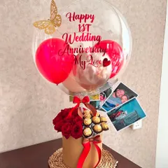 We love adding personal touches to our anniversary hampers. This first anniversary gift includes a box of red roses and Ferrero Rochers, a custom balloon, and even a few printed photos of the couple to make it truly unique.