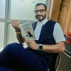 Holding a copy of "Justice and Jokes." This book is a must-read for anyone interested in the legal world, offering a glimpse into the struggles and lighter moments that define a lawyer's life.