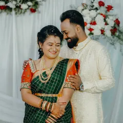 A happy couple captured during their South Indian wedding ceremony. The bride's green and orange Kanjeevaram saree and the groom's traditional kurta are documented in vibrant color.